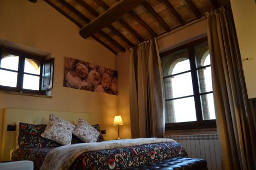 a bedroom with a bed and two windows at GH Borgo Pulciano Agriturismo in Montone