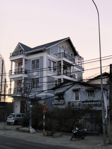 a white house with a scooter parked in front of it at Luan'S Villa in Da Lat