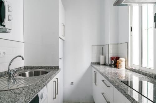 cocina blanca con fregadero y ventana en SVL - Sunny and bright apartment at historical Center, en Sevilla