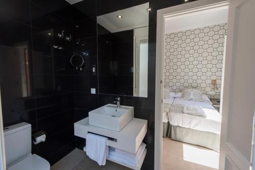 a bathroom with a sink and a bed and a mirror at Céntriko Apartments Francos in Seville