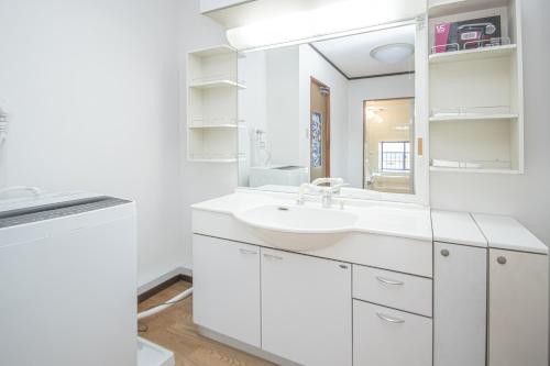 a white bathroom with a sink and a mirror at AMP FLAT Ogokusou in Fukuoka