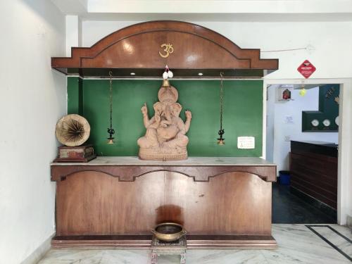 a statue in a room with a green wall at THE MAPLE in Siliguri