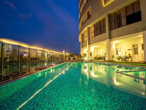 a swimming pool in front of a building at night at Golden Tulip Canaan Kampala in Kampala