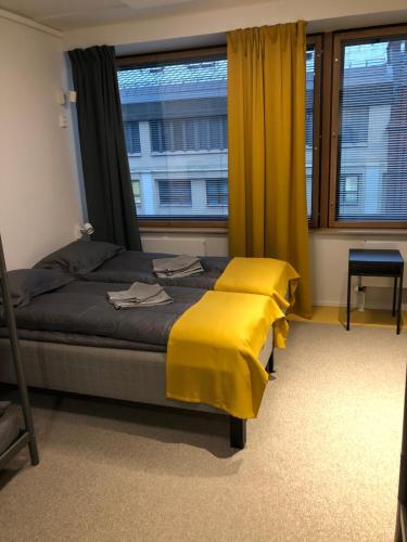 a bedroom with a bed with yellow sheets and a window at Aikatalo Hostel Helsinki in Helsinki