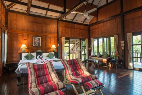 ein Schlafzimmer mit einem Bett und Stühlen in einem Zimmer in der Unterkunft ThaiLife Wellness & Meditation Resort- SHA Plus in Khao Lak