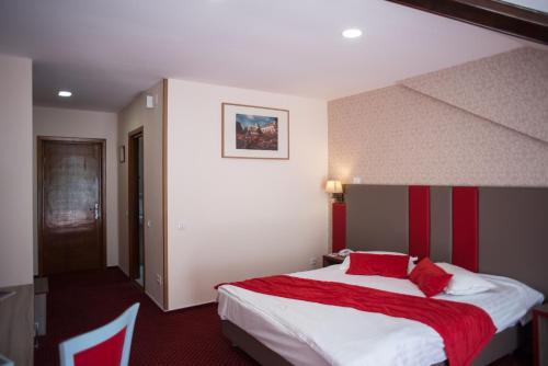 a bedroom with a large bed with red and white sheets at Hotel Marea Neagra in Sinaia
