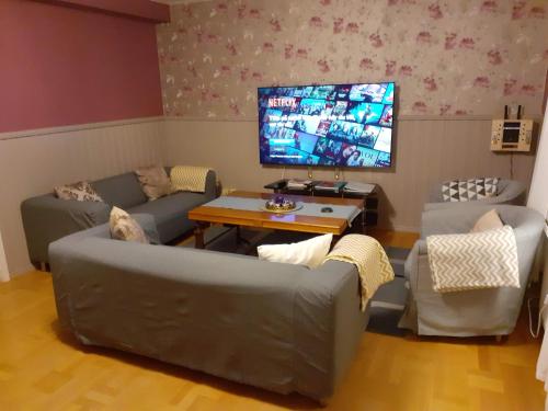 a living room with two couches and a flat screen tv at Holiday Home Byvägen 38 in Nattavaara