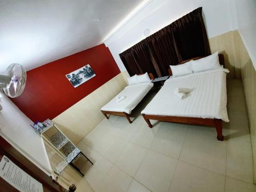 a bedroom with two beds and a red wall at Route 76 Guest House in Sen Monorom