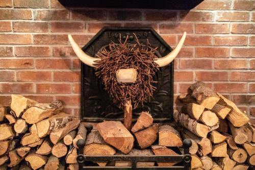 a fireplace with a bull skull with horns and logs at The Royal Oak in Loughborough