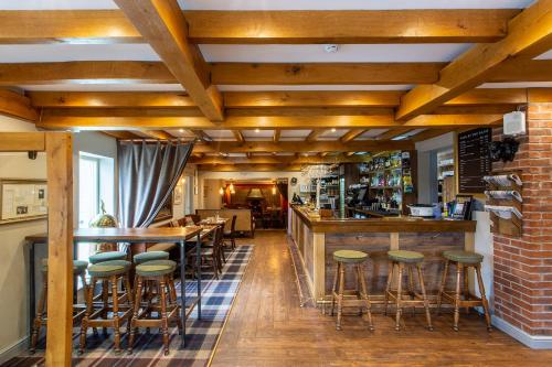 a bar in a restaurant with wooden ceilings and stools at The Royal Oak in Loughborough