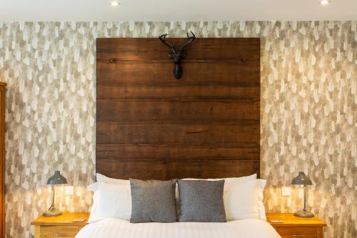 a bed with a wooden headboard and two lamps at The Royal Oak in Loughborough