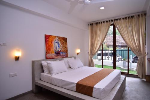 a bedroom with a large bed and a large window at Lily Holiday Apartments in Hikkaduwa