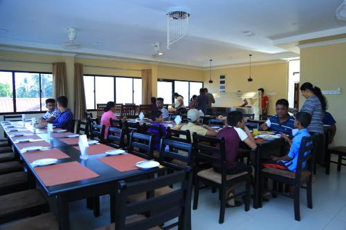 a group of people sitting at tables in a restaurant at PJ Hotels Jaffna in Jaffna