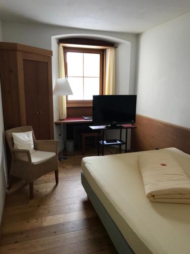 a bedroom with a bed and a desk with a computer at Hôtel Bodenhaus in Splügen