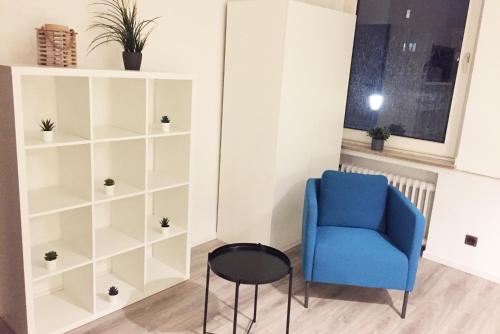 a room with a blue chair and a book shelf at Nice and cozy apartment with Wifi and balcony in Neuss