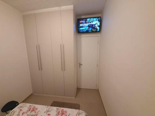 a bedroom with a bed and a tv on a wall at Apartamento Completo em Cotia - SP in Cotia