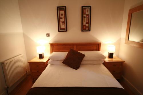 a bedroom with a bed with two lights on it at Chaucer Apartment in Keswick
