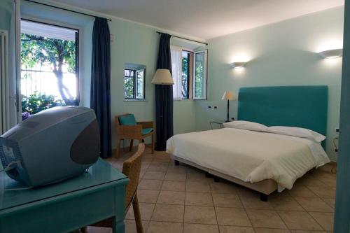 a bedroom with a bed and a desk with a tv at Locanda Conchiglia D'Oro in Varigotti
