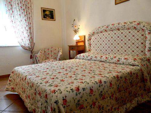 a bedroom with a bed with a flowered blanket and a chair at Il Campanile II Locazione Turistica in Pisa