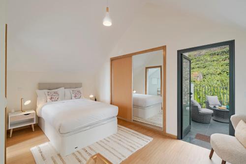 a bedroom with a white bed and a mirror at Oscar's House by An Island Apart in Ponta do Sol
