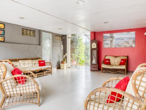 a living room with red walls and wicker chairs at OYO Praia Hotel Recanto do Tomé - Salvador in Paripe