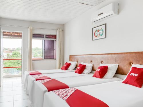 2 camas en una habitación con almohadas rojas y blancas en OYO Praia Hotel Recanto do Tomé - Salvador, en Paripe