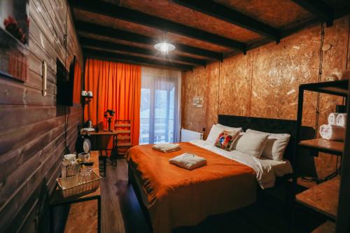 sypialnia z łóżkiem z pomarańczowym kocem w obiekcie Wooden Hotel Kazbegi w mieście Stepancminda