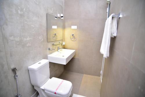 a bathroom with a white toilet and a sink at Lily Holiday Apartments in Hikkaduwa