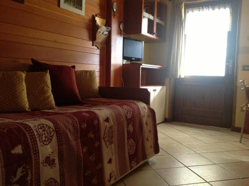 a bedroom with a bed and a window and a television at Residence Casa dei Fiori in Alagna Valsesia