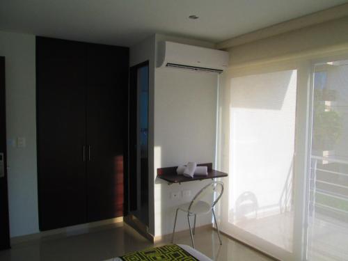 a bedroom with a black cabinet and a chair in front of a window at Hotel Ipanema Meridian in Neiva