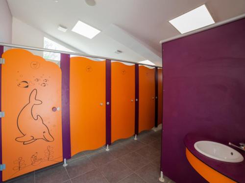 ein Badezimmer mit orangefarbenen und lila Ständen mit einem Hund an der Wand in der Unterkunft Oh! Campings - Le Clos du Rhône in Saintes-Maries-de-la-Mer
