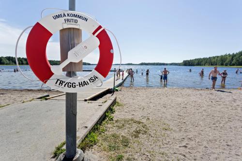 a sign on a beach with people in the water at First Camp Nydala-Umeå in Umeå