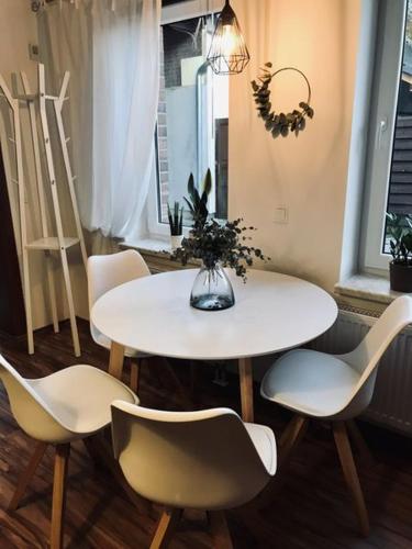 a white table with chairs and a vase of flowers on it at Ferienwohnung Willi I in Spremberg