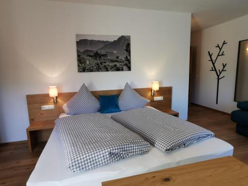 a bedroom with a large white bed with blue pillows at Pension Haus in der Sonne in Fieberbrunn
