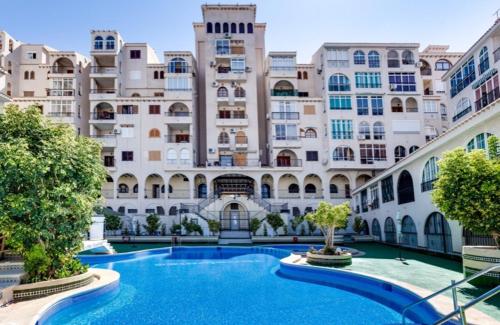 a large building with a swimming pool in front of it at Beautiful apartment near LaMata Beach with PANORAMA SEA view!!! in Torrevieja