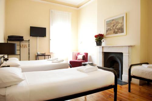 a hotel room with three beds and a fireplace at Hotel Claremont Guest House in Melbourne