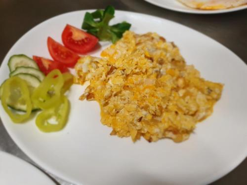 a white plate with scrambled eggs and vegetables on a table at Hotel Palatín in Oravský Podzámok