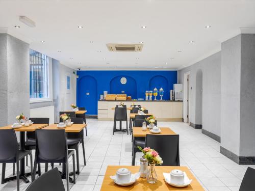 a dining room with tables and chairs and blue walls at OYO Townhouse Apollo, Hyde Park in London