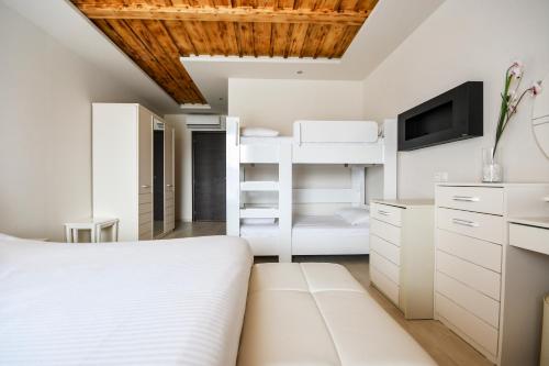 a bedroom with a white bed and a tv at Archontiko Liamas in Stavros