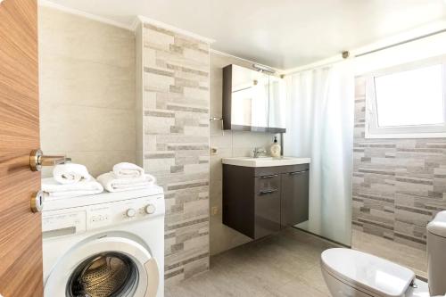 W łazience znajduje się pralka i umywalka. w obiekcie Οικια Elisabeth w mieście Artemida