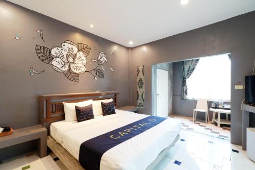 a bedroom with a large bed with flowers on the wall at Capital O 464 At Nata Chiangmai Chic Jungle in Mae Rim