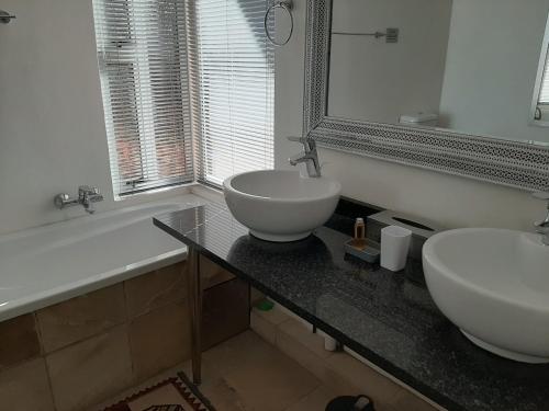 a bathroom with two sinks and a mirror and a tub at Orangerie Guest House in Johannesburg