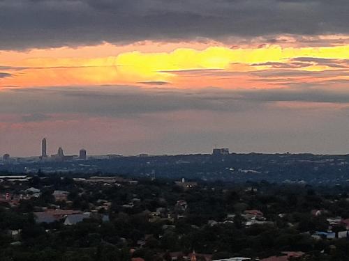 a view of a city with a sunset in the sky at Orangerie Guest House in Johannesburg