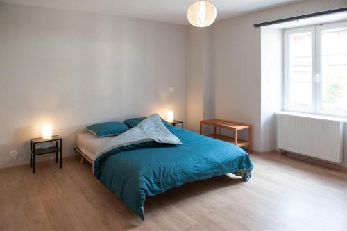 una camera da letto con un letto con lenzuola blu e una finestra di LE TOMIGITE a Dimbsthal
