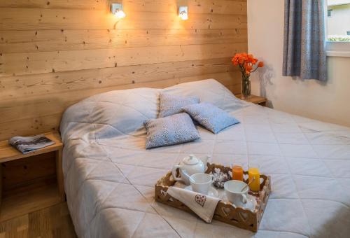 a bed with a tray of food and drinks on it at Hôtel Restaurant Les Tilleuls in Autrans