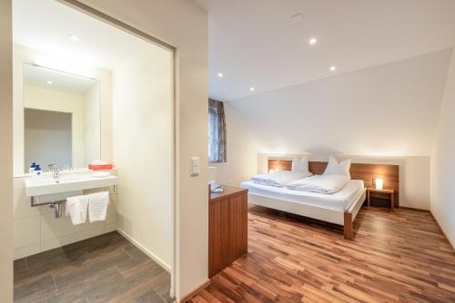 a bedroom with a bed and a sink and a mirror at Hotel Rössli in Zuzwil