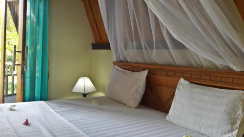 a bedroom with a bed with a canopy and a window at Pandan Bungalow in Gili Air