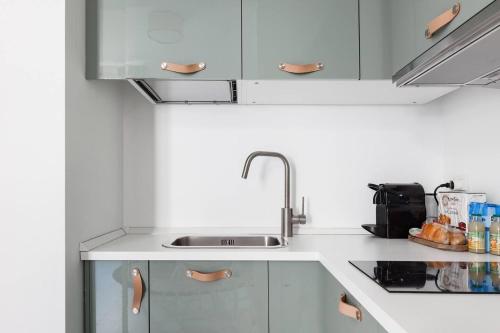 een keuken met witte kasten en een wastafel bij Elegante appartamento minimal dai tocchi botanici in Milaan