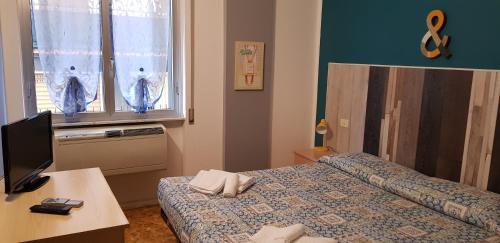 a room with two beds and a desk and a television at Hotel La Torre in Cogoleto