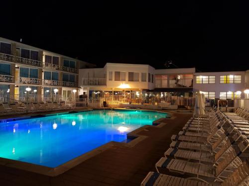 a swimming pool with chairs and a hotel at night at The Jolly Roger Motel in Wildwood Crest